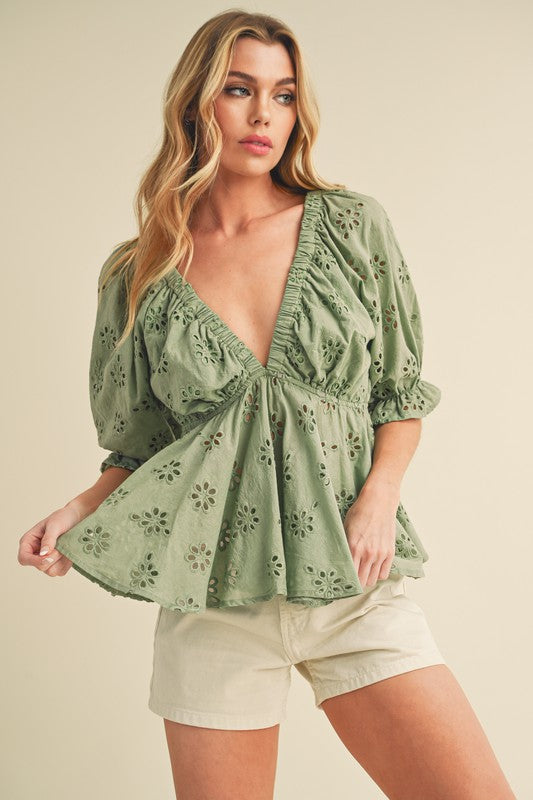 This charming top features delicate eyelet embroidery, feminine ruffles, and a flattering cinched waist.